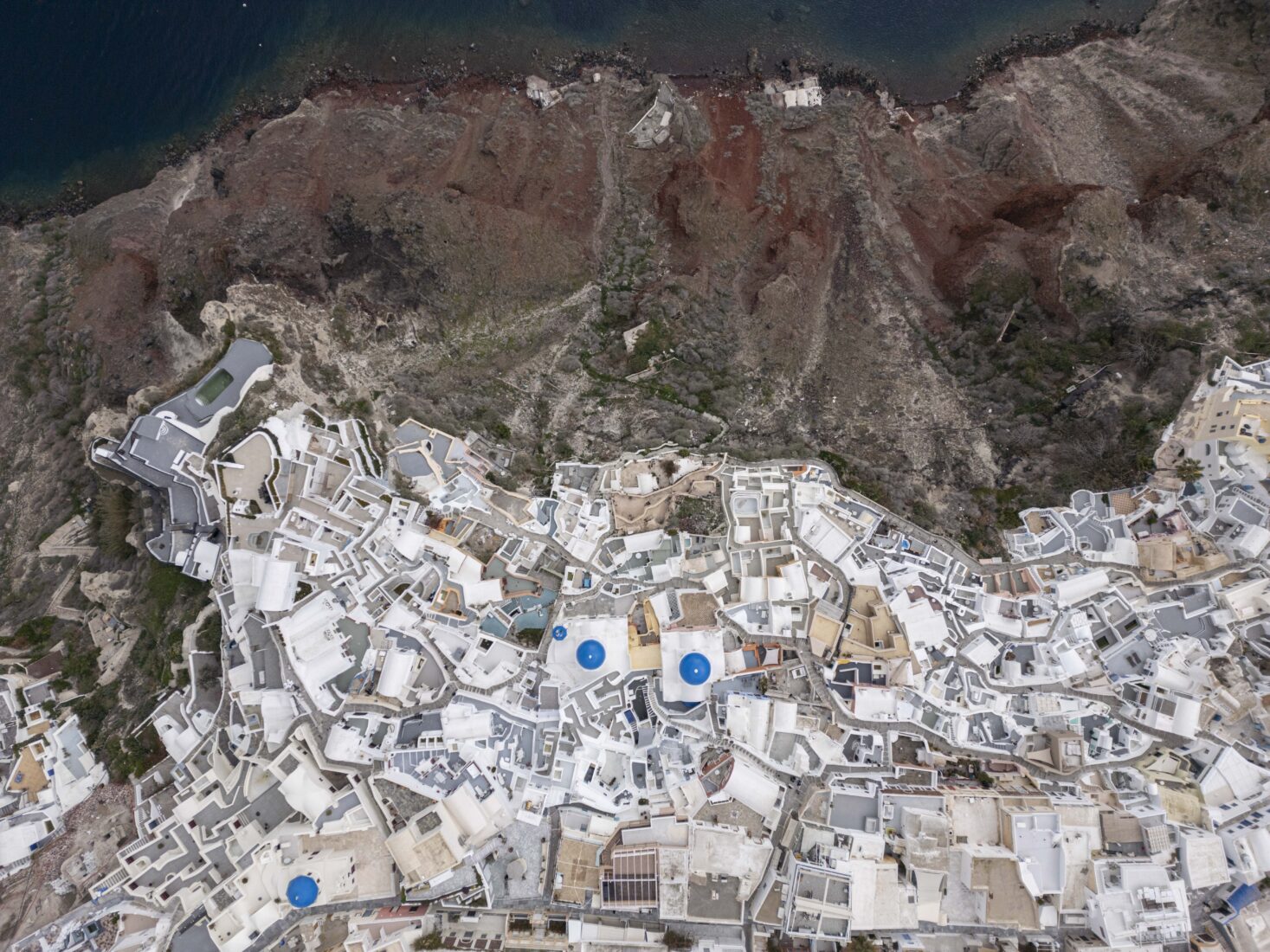 A drone view of the Blue Domed Church and the surrounding village of Oia, Santorini.