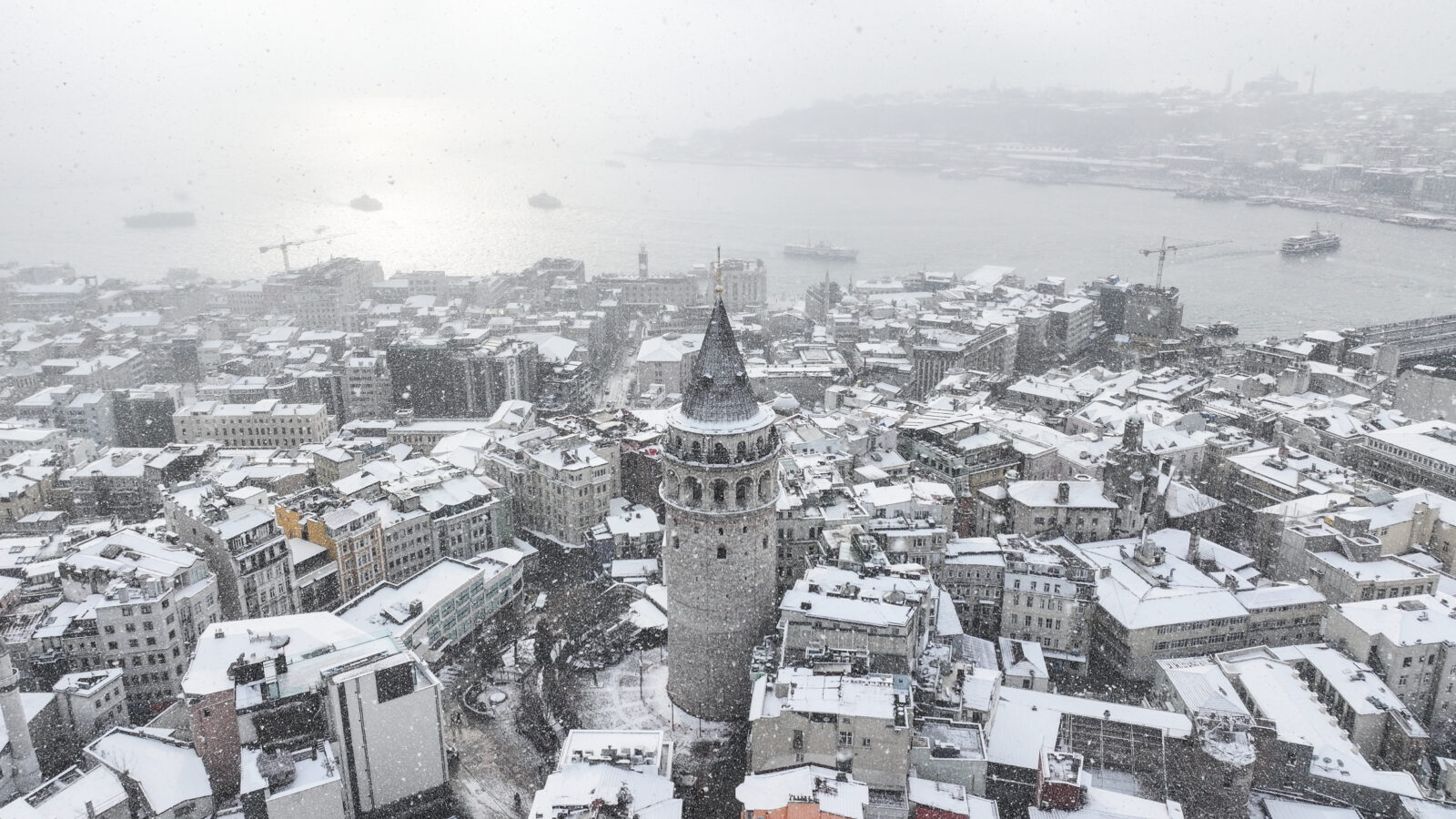 Aerial view of Galata Tower surrounded by snow in Istanbul, Türkiye.