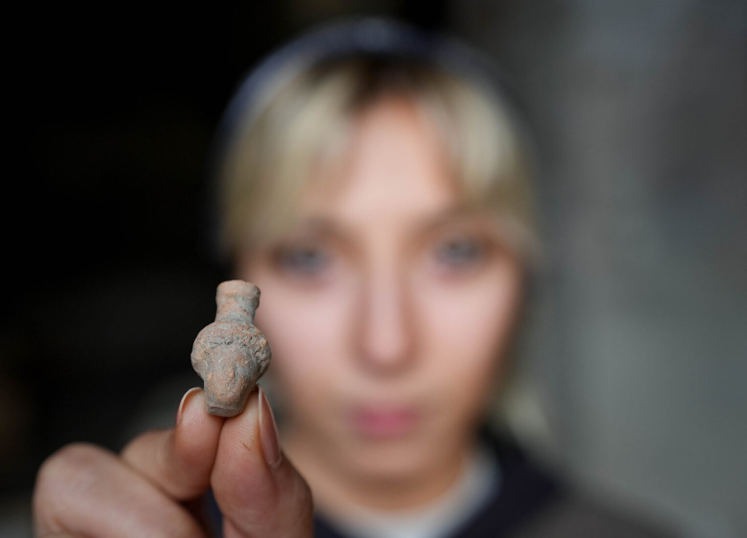 A female archaeologist displays a small artifact found at the 