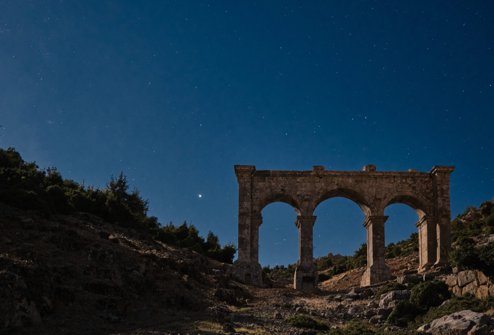 A night view of ancient stone arches under a starry sky, ideal for stargazing.