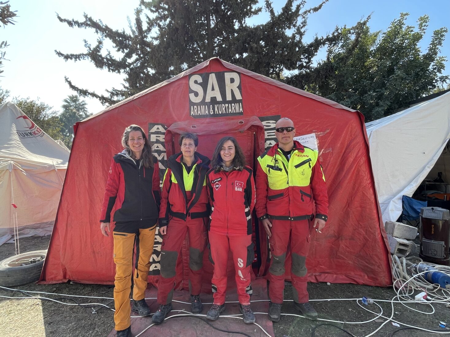 Search-and-rescue workers from Turkey and the Netherlands in front of a red SAR tent