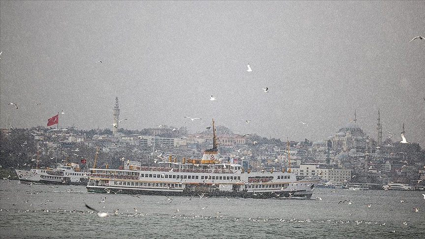A ferry sails through the Bosphorus in Istanbul amid snowfall, with the city