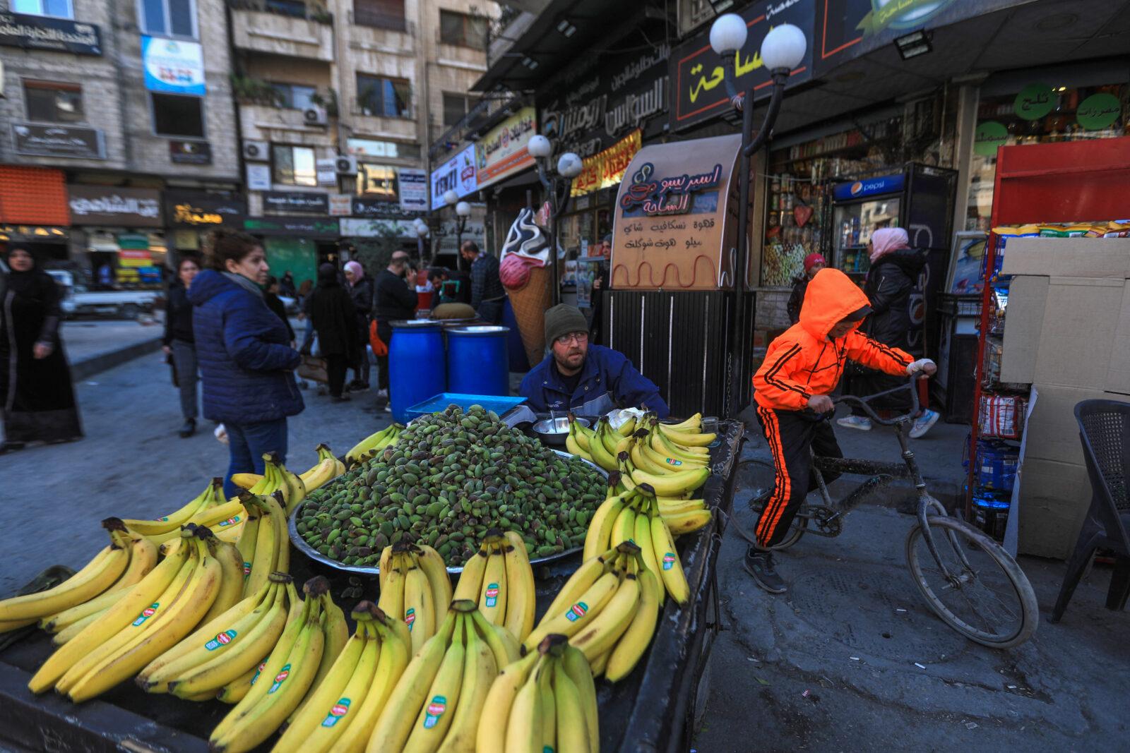 Syrian families in damascus in open market with banana stand