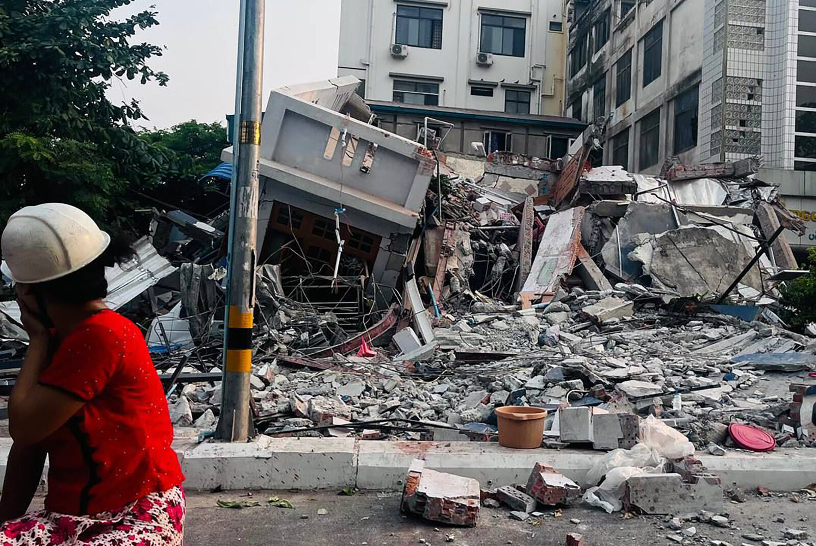 Photo shows a resident looking on next to a collapsed building.