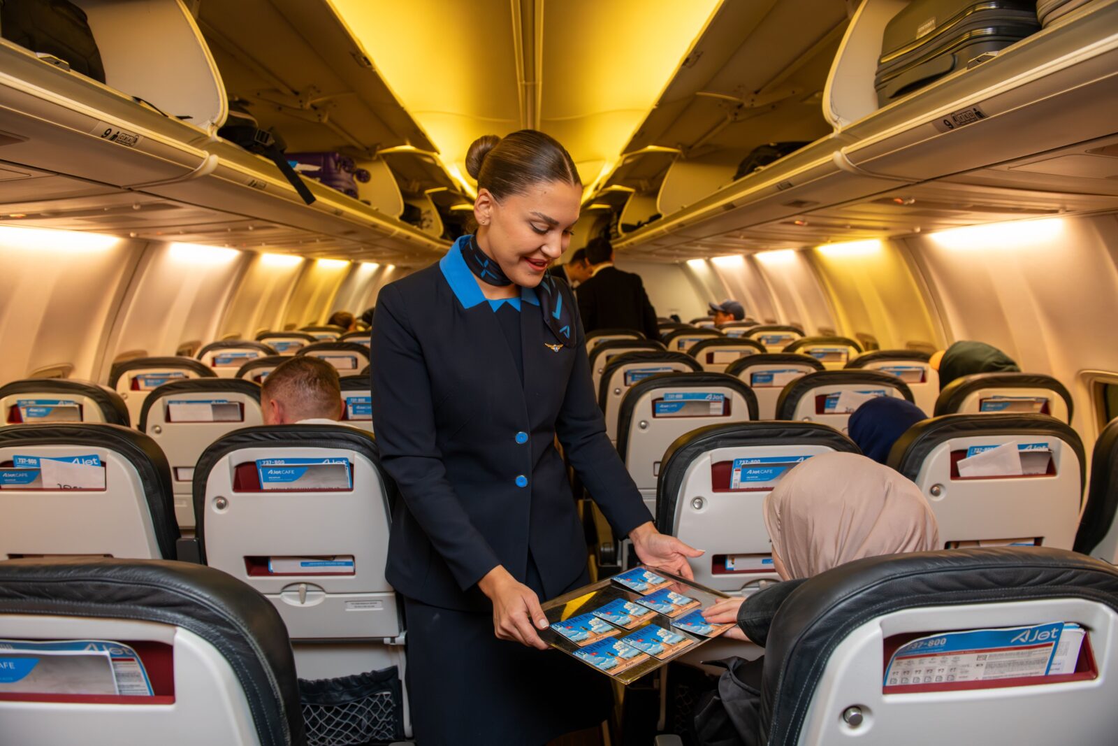 A flight attendant assisting a passenger aboard an AJet aircraft