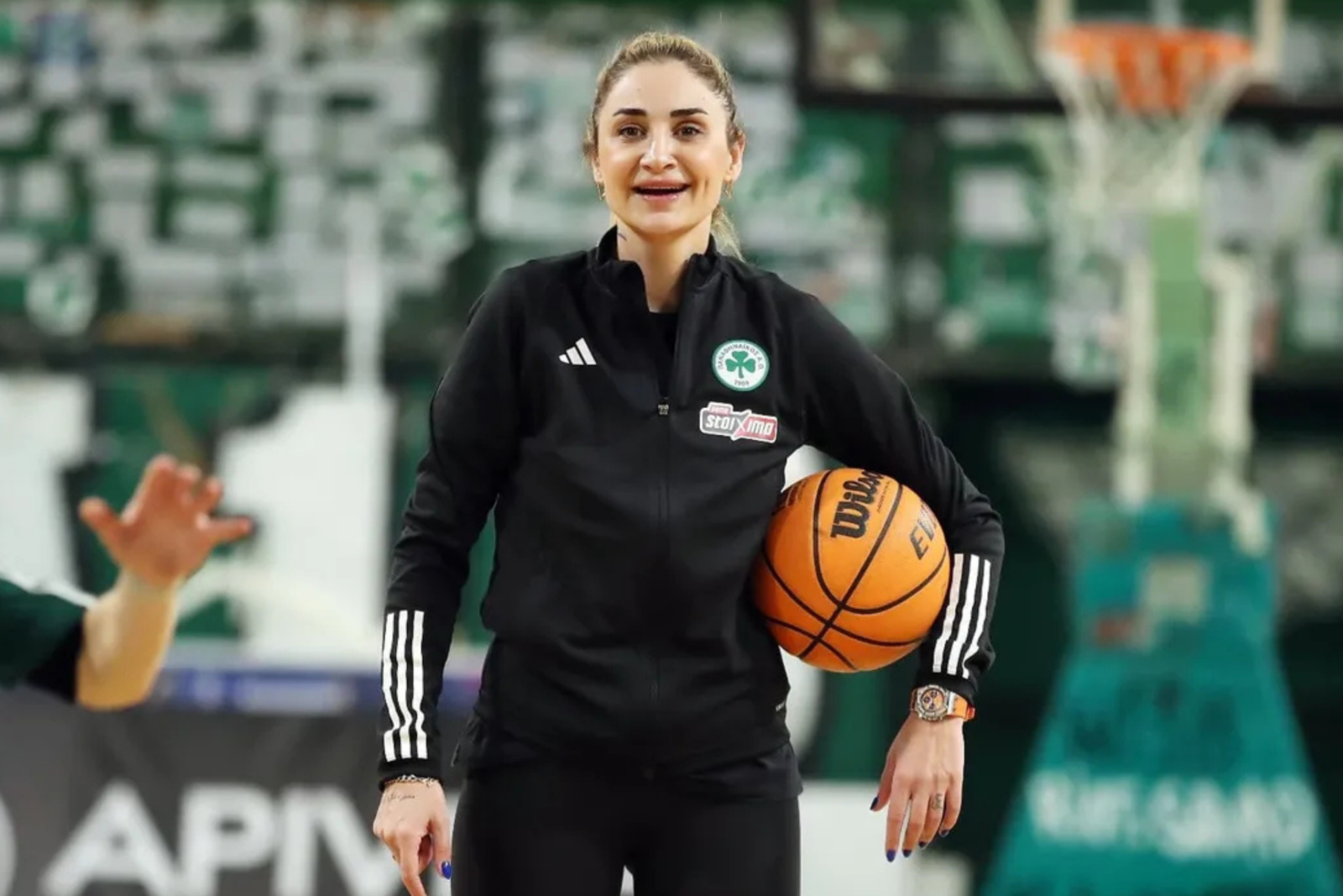Turkish coach Selen Erdem smiling while holding a basketball during a training session.