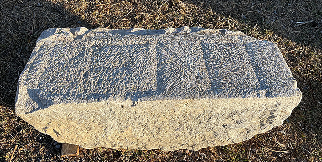A weathered stone block from Teos, Türkiye, showing traces of a deliberately erased inscription. The markings became visible under winter light conditions.