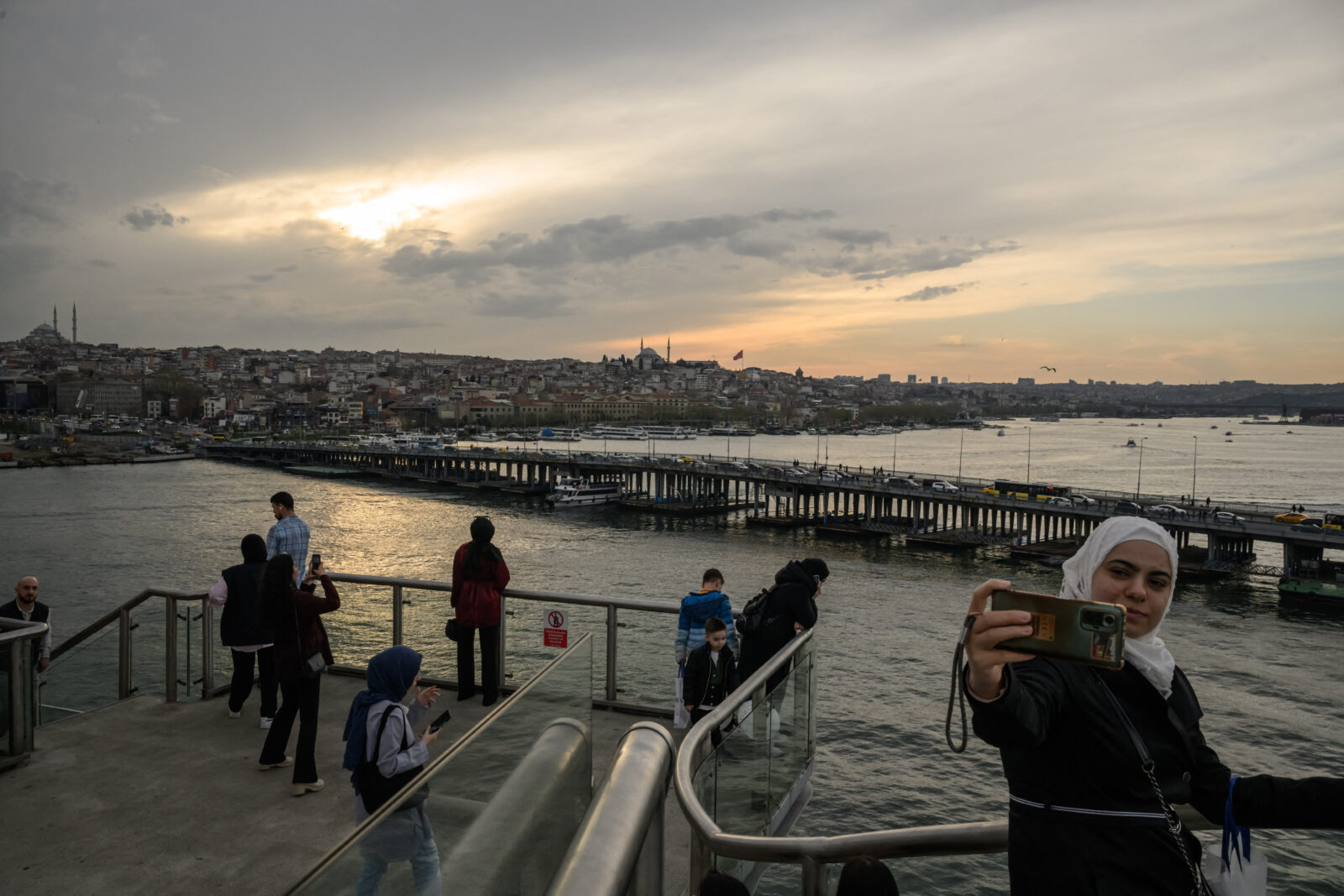 People stand on the Halic Golden Horn Metro Bridge
