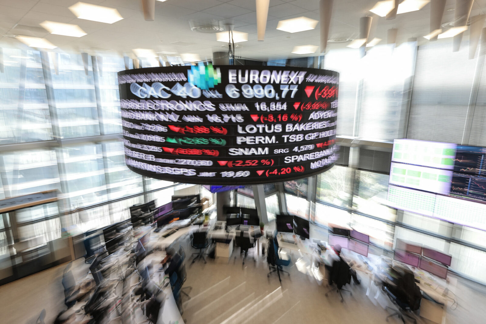 Traders work below digital board