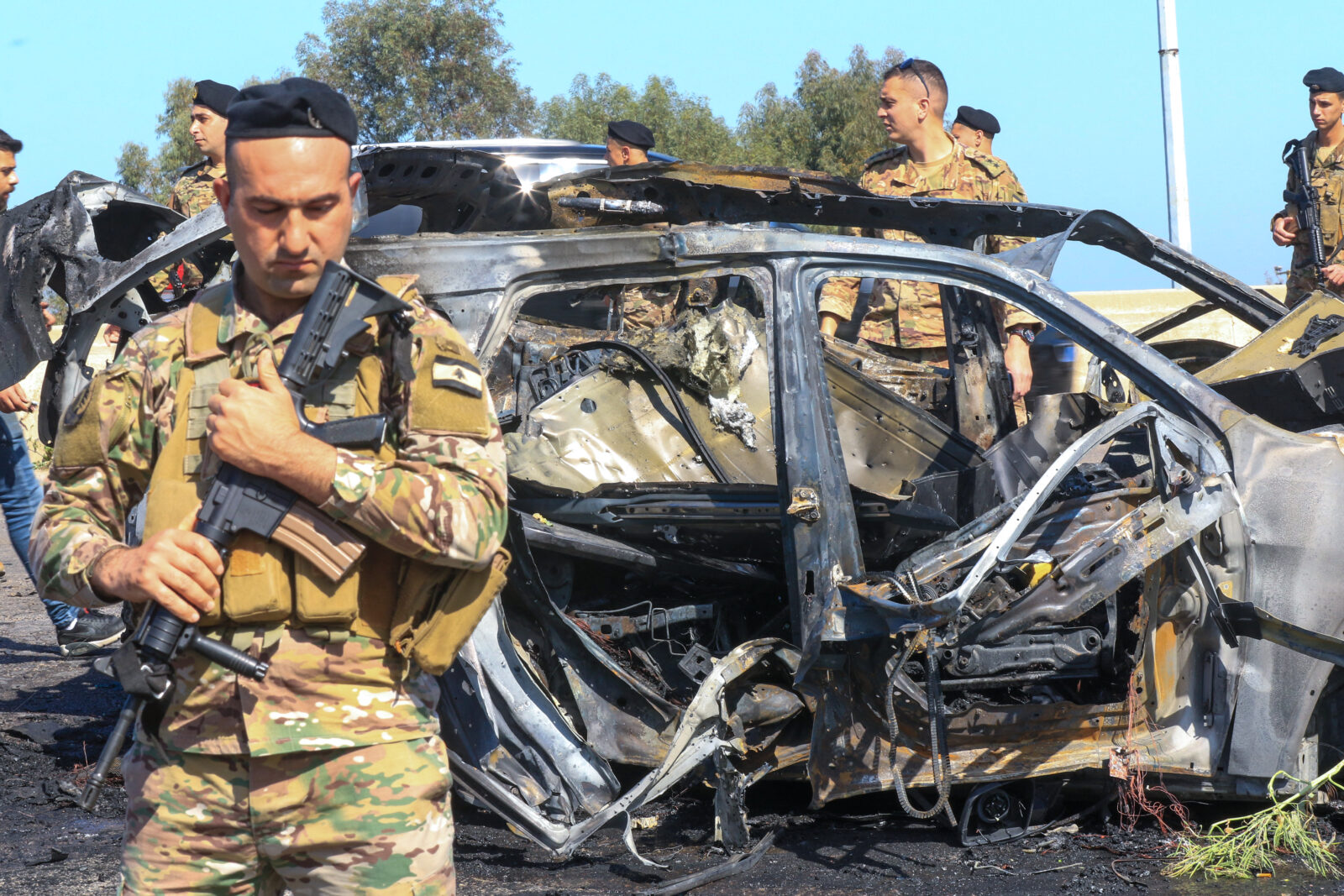 Lebanese soldiers inspect the site near a burnt-out vehicle reportedly hit by an Israeli strike in Ghazieh, near Sidon