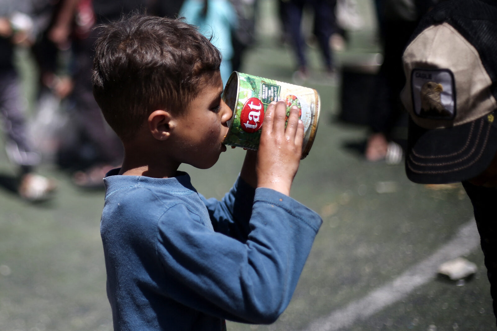 A Palestinian child eats his portion of a hot meal at a free food distribution point at the Nuseirat refugee camp in the central Gaza Strip